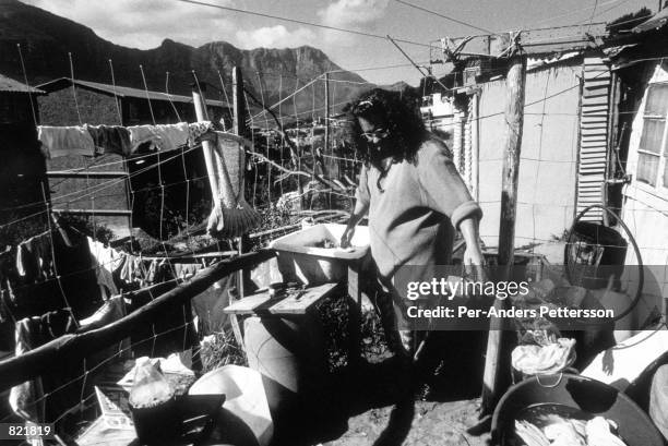 Lynette Matthe does the laundry outside her family's shack September 27, 1998 in Hout Bay outside Cape Town, South Africa. She lives with her...