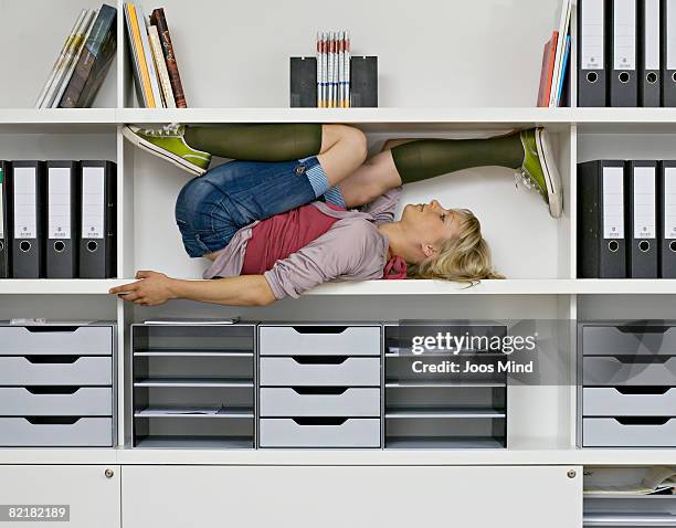 young woman stretching in office shelves - bizarre office stock pictures, royalty-free photos & images