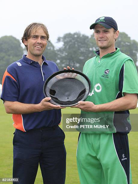 Jerome Smits , captain of the Dutch cricket team and William Porterfield, captain of Ireland pose for photographs with the qualifying trophy after...