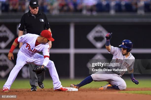 Jose Altuve of the Houston Astros slides safely into second base on a double before the tag from Cesar Hernandez of the Philadelphia Phillies in the...