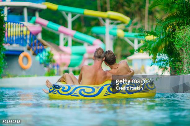 homosexuelle paare - männer - spaß im wasserpark - inflatable ring stock-fotos und bilder