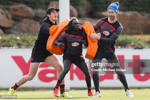 Anthony McDonald-Tipungwuti of the Bombers cops heavy bags from Michael Hartley and Shaun McKernan during an Essendon Bombers AFL media session at...