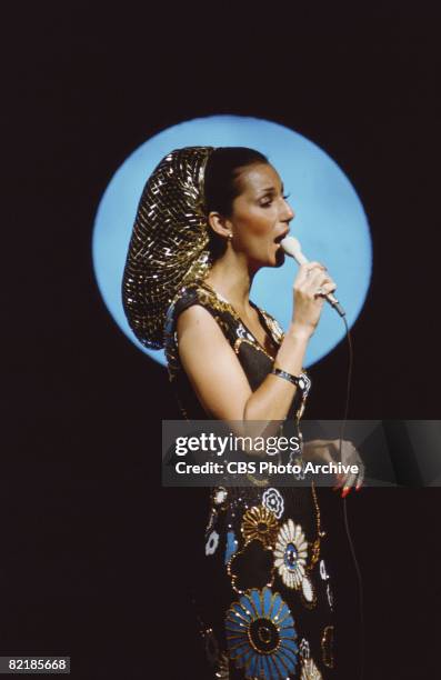 Promotional portrait of American singer and actress Cher as she sings into a microphone for the television variety show 'The Sonny and Cher Comedy...