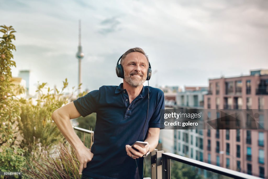 Hübscher midaged bärtigen mit Kopfhörern auf Balkon in Berlin