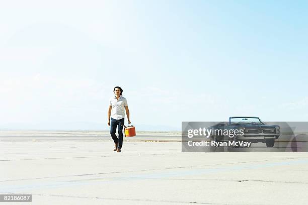 man walking away from car with gas can - benzinekan stockfoto's en -beelden