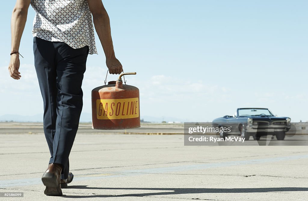 Man walking toward car with gas can