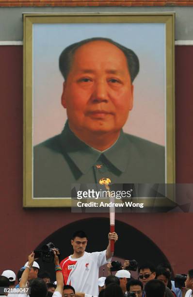 China's NBA star Yao Ming carries the Olympic torch underneath a giant portrait of the late chairman Mao Zedong on Tiananmen Square during the...