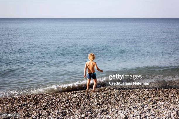 rear view of boy at beach - boy exploring on beach stock pictures, royalty-free photos & images