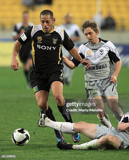 Leo Bertos of the Phoenix is tackled by Sebastian Ryall and Mathew Kemp of the Victory during the 2008 A-League Pre-Season Cup match between the...