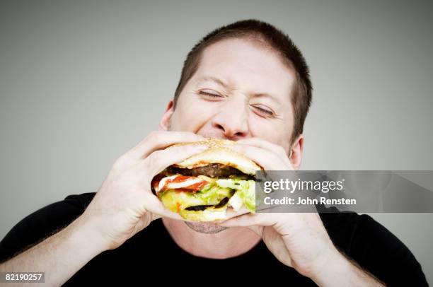 man eating burger - hamburger stock pictures, royalty-free photos & images