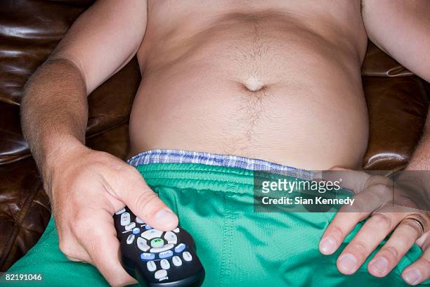 overweight man trying on clothing - couch potato stock-fotos und bilder