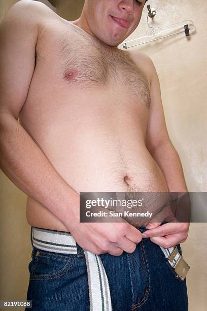overweight man trying on clothing - man buttoning jeans stock pictures, royalty-free photos & images