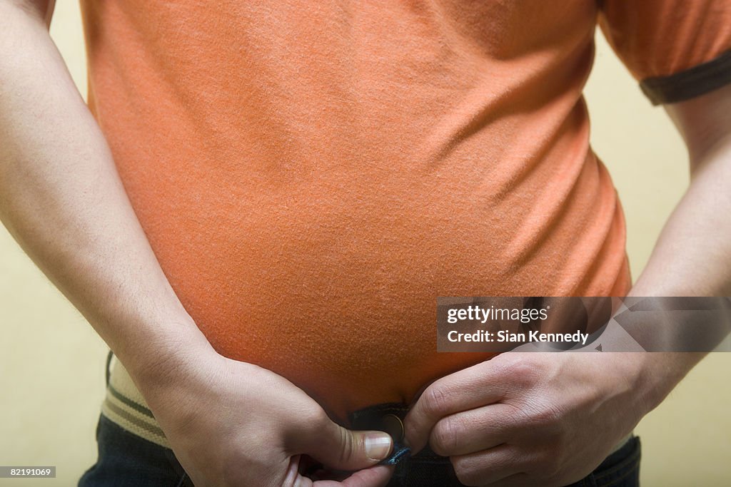 Man with pot belly trying on pants