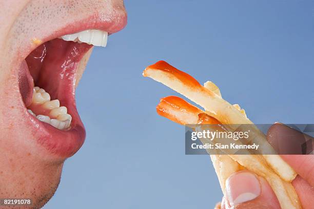 close-up of someone eating french fries - french fries foto e immagini stock