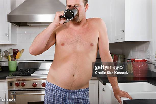 man with pot belly drinking coffee - human abdomen foto e immagini stock