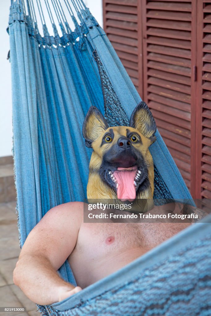 Man with dog mask resting in a hammock