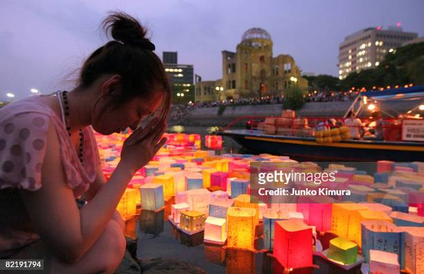 Woman prays at Motoyasu River in front of the Atomic Bomb Dome at the Peace Memorial Park, in memory of the victims of the bomb on the 63rd...