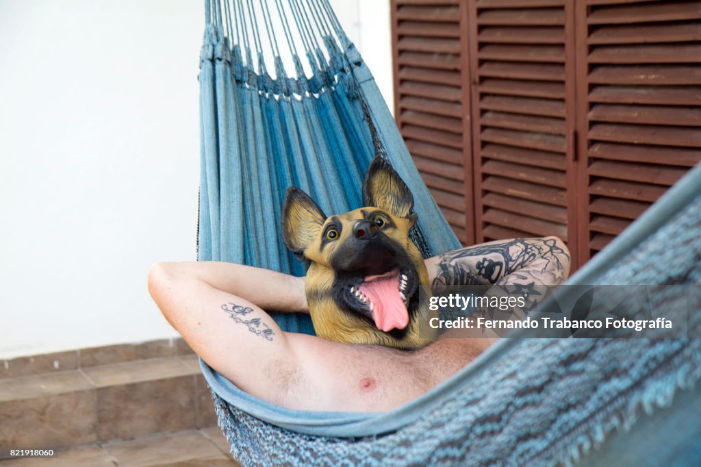 Man with dog mask resting in a hammock