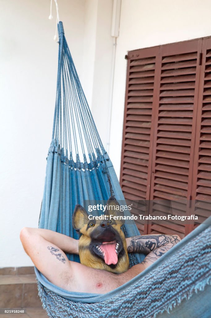 Man with dog mask resting in a hammock