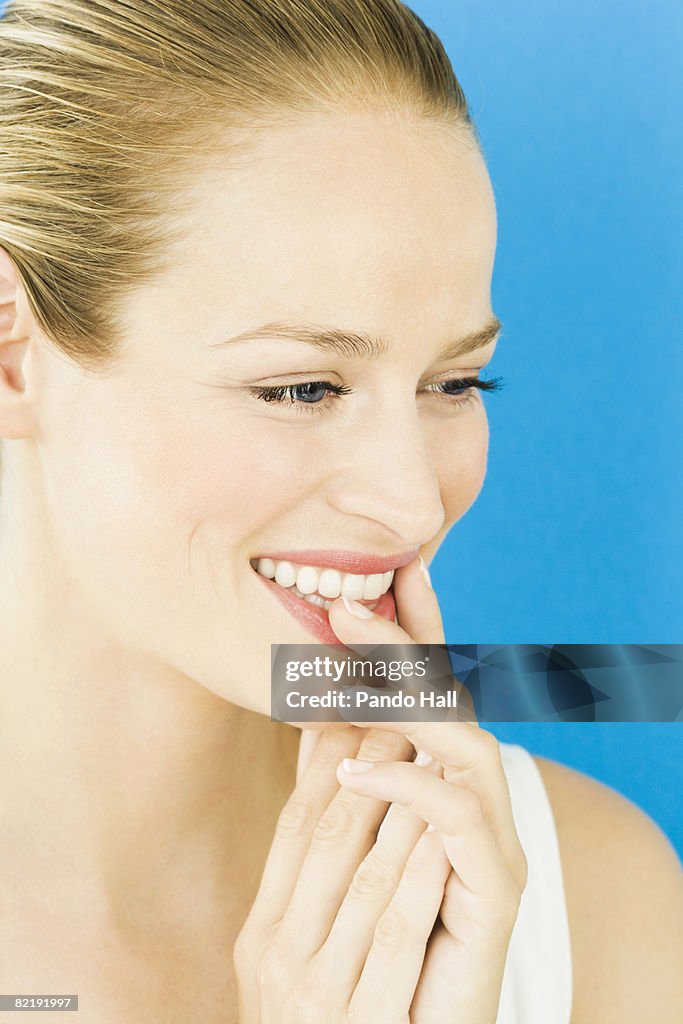 Woman with fingers on lips smiling, portrait