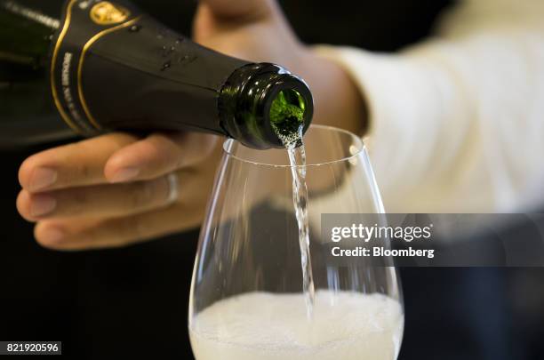 Member of the Japan Awasake Association pours a glass of sparkling sake at the association's booth during a Sake Marche event held at the Isetan...