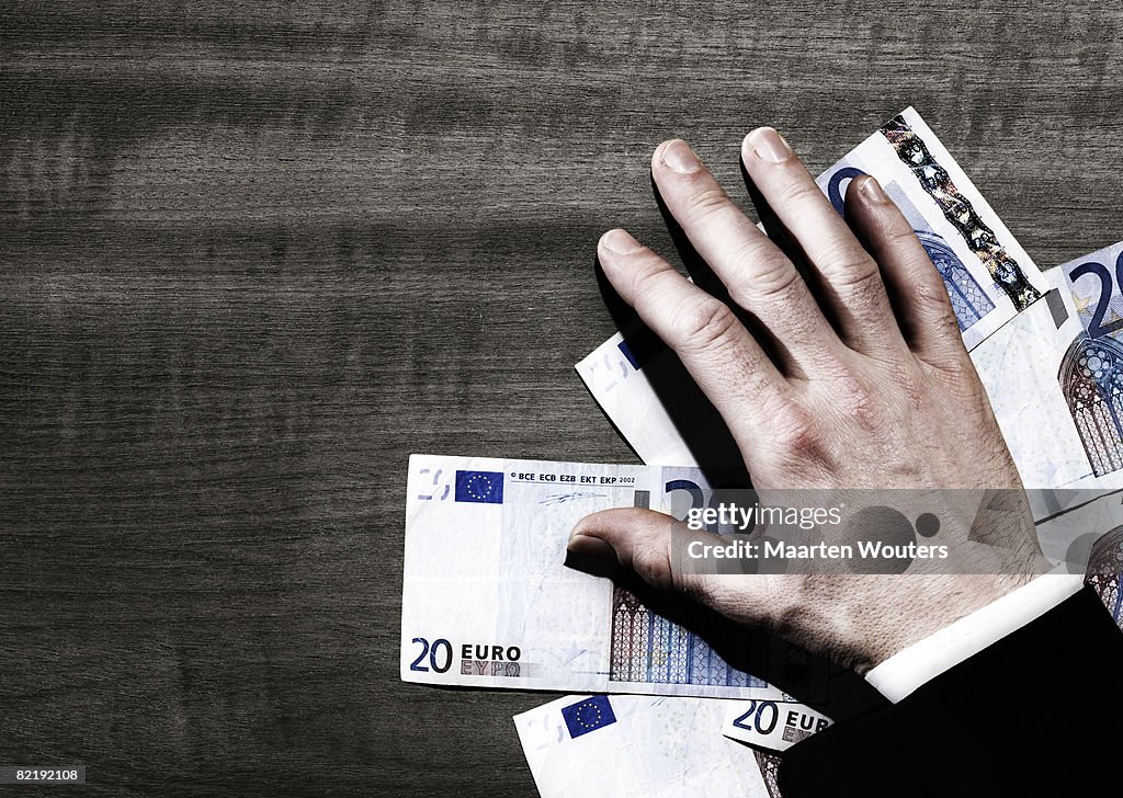 Man's hand with euro notes on ta
