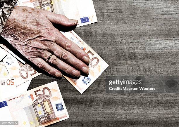 hand of elderly woman on table with euro  - pensioen thema stockfoto's en -beelden
