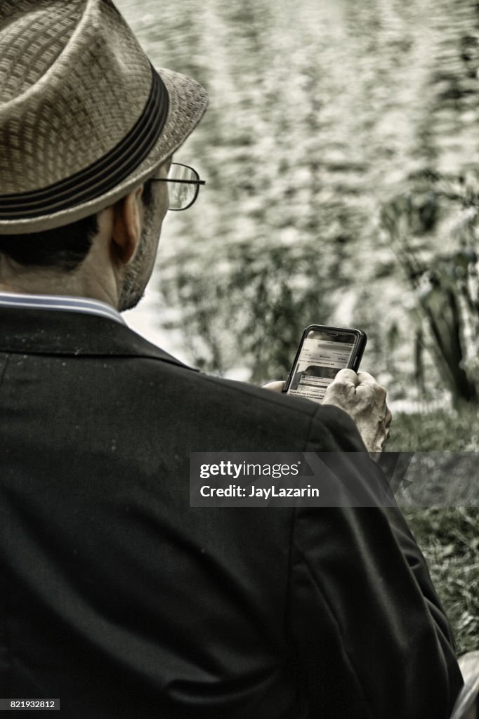 Homem usando Smartphone, segurando o dispositivo na frente dele.