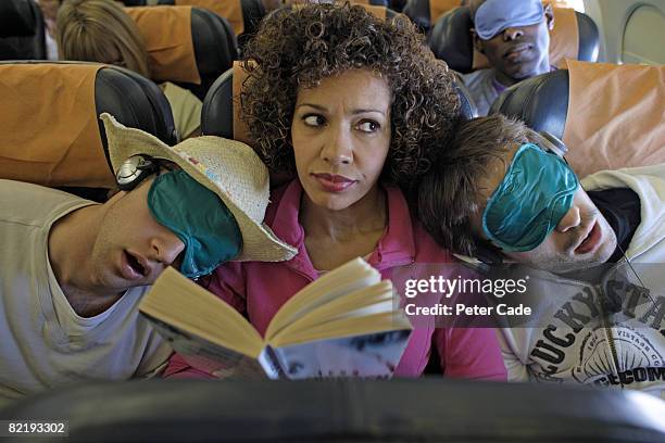 woman sat on plane two men asleep on her shoulders - incómodo fotografías e imágenes de stock