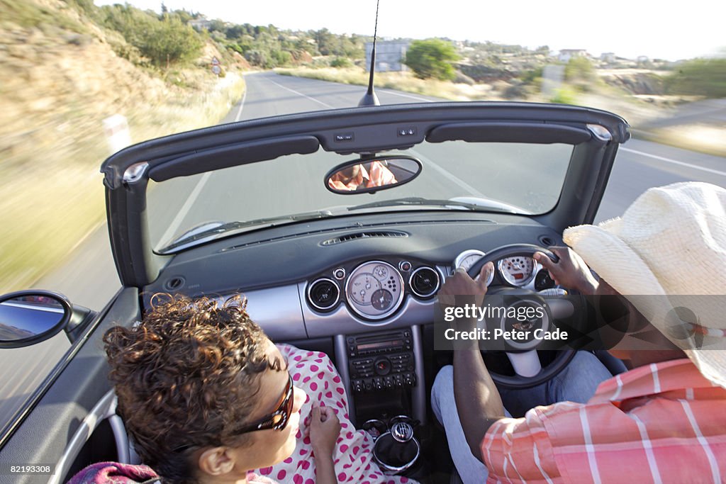 Man and woman driving in car with roof down
