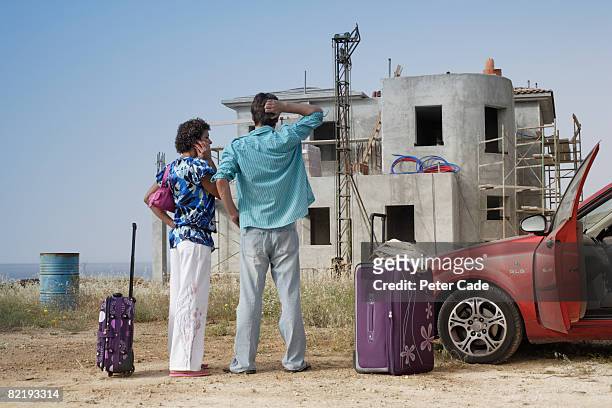 couple stood in front of half built villa - delusione foto e immagini stock