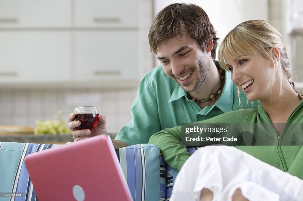 Couple drinking wine looking at laptop