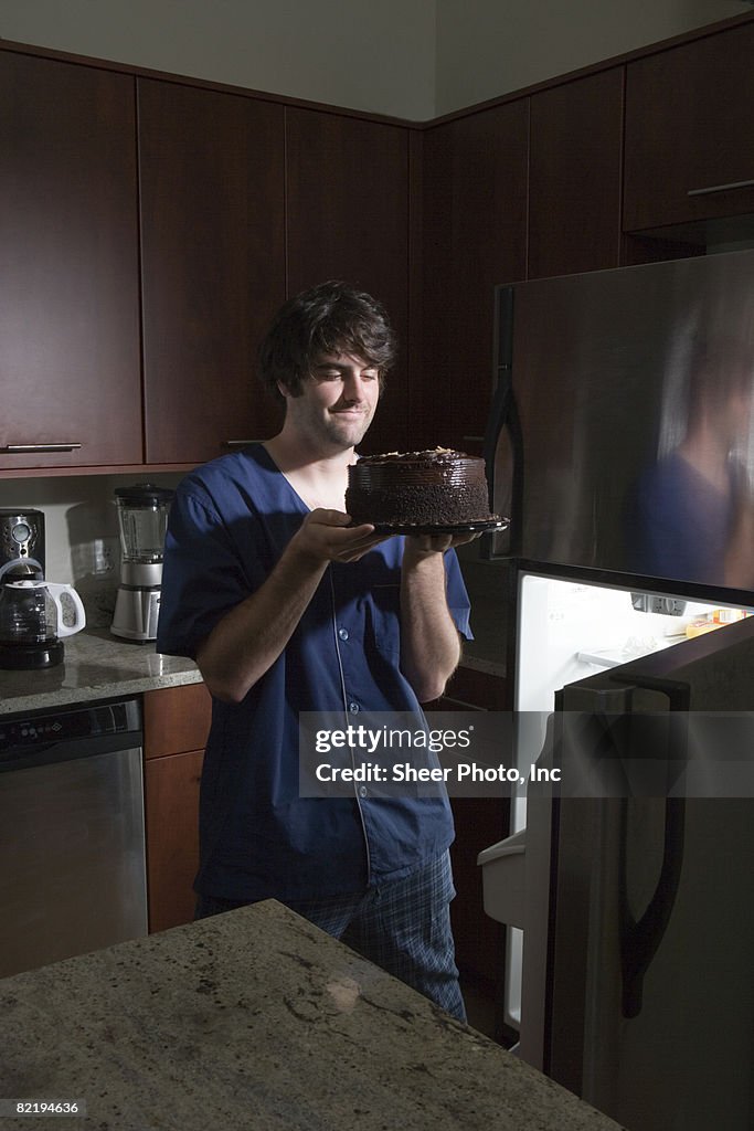 Man withrefrigerator holding chocolate cake