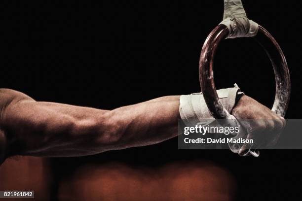 gymnast performing on still rings - acrobatic stock pictures, royalty-free photos & images