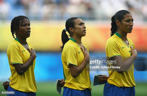 Formiga, Marta and Daniela of Brazil line up for the national anthem before the women's preliminary group F match between Germany and Brazil at...