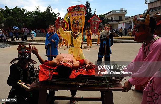 Villagers stand around a bed of thorns as a Nuowu performer lays upon it, during the performance of Nuowu Dancing, an ancient dance with a history...