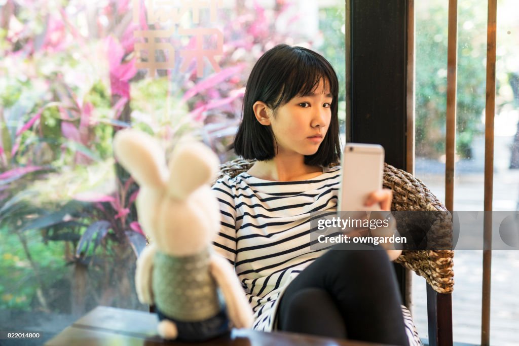 Teenage girl using smartphone in the restaurant