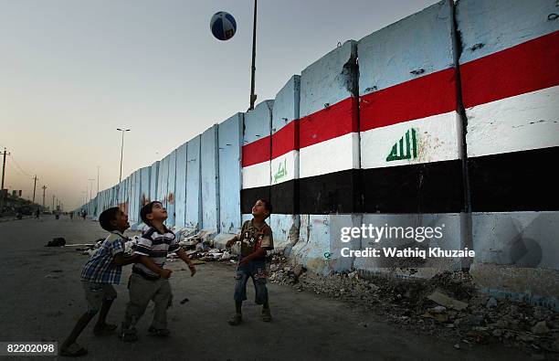 Iraqi children play football next to the security wall with an Iraqi flag painted on it, August 6, 2008 in the Shiite district of Sadr city east of...