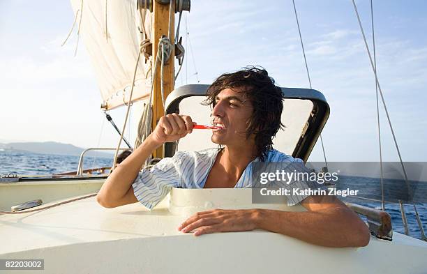 young man brushing his teeth on sailing boat - trappen photos et images de collection