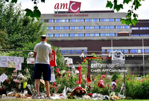 Visitor stands in silence next to items placed next to the hospital where the Ajax midfielder Abdelhak Nouri receives treatments in Amsterdam on July...