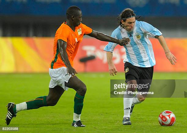 Lionel Messi of Argentina is challenged for the ball by Ousmane Viera Diarrassouba of Ivory Coast during Men's Group A match between Ivory Coast and...