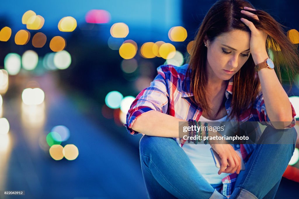 Depressed, young girl is standing sad on the bridge