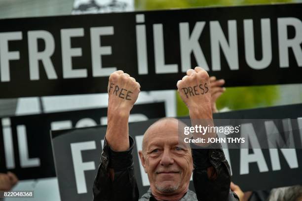 Man with the words 'free press' written on the backs of his hands protests alongside Amnesty International activists and partners outside the...