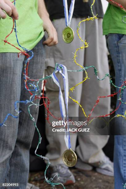 Israeli human rights activists hold replicas of Olympic medals and barbed wire in the colours of the Olympic Rings as they protest outside the...