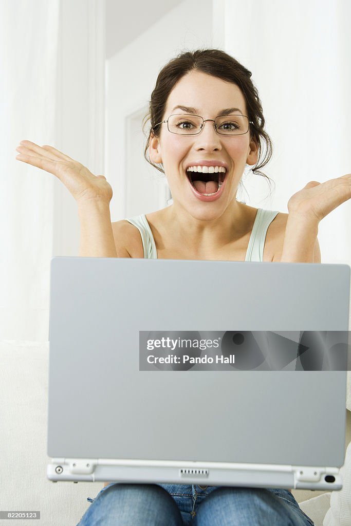 Young woman using laptop, eyes and mouth wide open