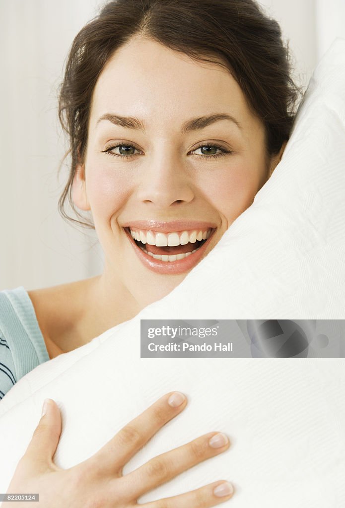 Young woman holding pillow, laugh