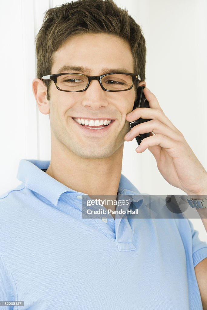 Young man using telephone, smiling