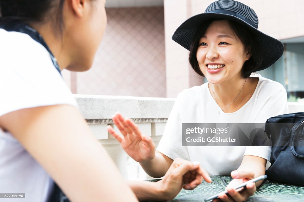 Koreaanse dame haar slimme telefoon tonen aan haar Japanse vriend