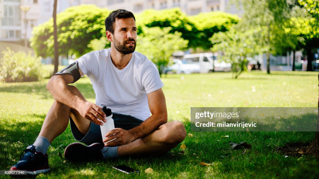 自然の中の訓練の後、地面に座って男