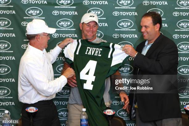 Brett Favre holds up his New York Jets jersey alongside Chairman and CEO Woody Johnson and Executive Vice President/General Manager Mike Tannenbaum...